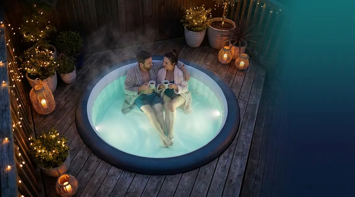 Couple relaxing in the best saltwater hot tub on an outdoor deck at dusk